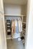 Organized walk-in closet with neatly hung clothes, shelves for shoes, and additional storage compartments.