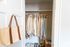 Organized walk-in closet featuring neutral clothing, neatly arranged shoes, and rolled towels for a tidy and spacious feel.