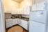 Charming kitchen with white cabinets, modern appliances, and cozy wooden flooring offers perfect functionality and style.
