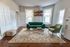Charming living room featuring a plush green sofa, elegant armchair, and a stylish area rug, bathed in natural light from large windows.