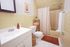 Charming, well-lit bathroom featuring vintage yellow tiles, a modern white vanity, and elegant decor for a cozy touch.
