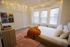 Cozy bedroom with soft lighting, a plush orange throw on a modern bed, and artistic vinyls creating a warm and inviting atmosphere.