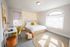 Bright and cozy bedroom featuring a stylish bed with accent pillows, a workspace with a modern chair, and ambient string lights.