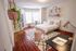 Bright and inviting bedroom with elegant decor, featuring a cozy bed, stylish workspace, and lush hanging plant.
