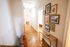 Charming hallway with bright lighting, exquisite wooden floors, and elegant framed artwork leading to cozy rooms.