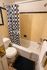 Charming bathroom with retro yellow tile, modern white fixtures, and a stylish black and white checkered shower curtain.