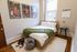 Cozy bedroom with wooden bed frame, green knit throw, and stylish decor featuring basketball artwork and a March calendar.