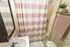 Charming bathroom with a cozy, fresh style featuring a pink and white striped shower curtain, elegant vanity, and plush pink towels.