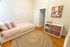 Cozy bedroom with a modern aesthetic, featuring a soft pink bed, stylish neon wall art, and ample storage solutions.