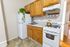 Cozy kitchen with wooden cabinets, a white fridge, and a charming vine plant. Includes a classic gas stove and a sleek white countertop.