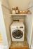 Compact laundry nook featuring a modern LG washer, stylish shelving with decorative items, and practical storage.