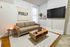 Cozy modern living room featuring a plush beige sofa, elegant wood coffee table, wall-mounted TV, and a calming salt lamp ambiance.