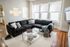 Bright and inviting living room with large sectional sofa, modern glass coffee table, and abundant natural light from expansive windows.