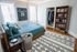 Bright and stylish bedroom with sporty decor, featuring a cozy bed, elegant bookshelf, and ample closet space for modern living.