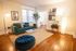 Inviting living room with a stylish teal sofa, chic decor, and warm wooden floors, perfect for relaxation and entertainment.