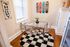 Chic dining nook with a modern glass table, clear chairs, and vibrant skateboard decor, enhanced by natural light and a stylish black-and-white rug.