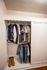 Charming closet space showcasing neatly arranged clothing and stylish footwear, highlighting efficient storage solutions in a cozy apartment.