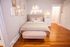 Chic bedroom with elegant artwork, cozy beige bedding, and a trendy 'hello gorgeous' neon sign, creating a warm and inviting atmosphere.