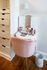 Chic vanity setup featuring a plush pink chair, elegant mirror, and neatly arranged makeup essentials on a wooden floor.