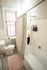 Bright and cozy bathroom featuring a classic white bathtub with a chic beige shower curtain, elegant tiled walls, and a plush pink bath mat for added comfort.