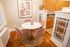 Charming dining nook with a round marble table, pink velvet chairs, and warm wooden cabinetry, perfect for cozy meals.