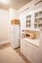 Charming kitchen showcasing a vintage white cabinet, modern appliances, and a cozy woven rug creating a warm, inviting atmosphere.