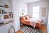 Cozy bedroom with warm decor, featuring a comfortable bed, stylish wall art, and a bookshelf filled with colorful books.