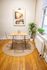 Chic dining nook with clear chairs around a wooden table, accented with green plants and elegant wall art.