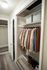 Organized walk-in closet showcasing neatly arranged clothes on hangers, stylish storage bins, and a pristine wooden floor with shoes neatly lined up.