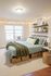 Cozy bedroom with stylish decor, featuring a soft bed with decorative pillows, warm fairy lights, and elegant shelf displays with plants.