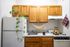 Charming kitchen with wooden cabinets, lush green plant on the fridge, and cozy decor, perfect for a warm and inviting home.