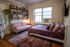 Charming studio apartment featuring a cozy bed, stylish sofa, and decorative wall-mounted shelves in an inviting living space.