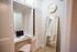 Charming workspace corner featuring a sleek desk with a laptop and book, enhanced by a stylish full-length mirror and modern decor.