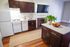 Bright and inviting kitchen featuring elegant dark wood cabinetry, a modern flat-screen TV, and a cozy fireplace. Complemented by a sleek kitchen island with fresh fruit and a vibrant plant, offering a warm and homely atmosphere.