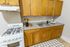 Charming kitchen with warm wooden cabinets, modern stove, and sleek countertops enhanced by minimalist decor.