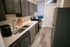 Modern galley kitchen featuring sleek dark cabinets, stainless steel appliances, and elegant wood flooring.