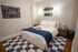 Inviting modern bedroom with elegant white bed, stylish blue accents, and creative wall art, exuding comfort and chic design.