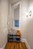 Charming corner nook featuring a sleek shoe rack with stylish sneakers and boots, illuminated by a modern wall sconce.