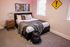 Inviting bedroom with modern decor, showcasing a cozy bed with plush pillows and a chic side table, accented by vibrant comic art and a unique yellow wall sign.