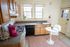 Charming kitchen with wooden cabinets, a cozy breakfast nook, and ample natural light filtering through large windows.