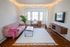 Bright and cozy living room with a stylish pink sofa, sleek modern desk, and soothing decor, enhanced by warm string lights.
