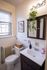 Charming bathroom featuring a classic design with a white vanity, elegant mirror cabinet, and vibrant potted plant, accentuated by natural light.