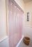 Charming bathroom with clean white tiles, a pink shower curtain, and a wicker basket adding rustic elegance.