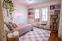 Charming bedroom with stylish decor, featuring a pink neon sign, cozy bed with soft pillows, inviting natural light, and a vintage record player.