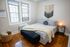 Cozy bedroom with soft lighting, stylish woven wall art, and elegant hardwood floors.