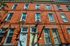 Charming red brick apartment building with classic architectural details and plentiful windows, nestled on a sunlit street.