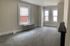 Bright and airy room with large windows, plush carpet, and sleek radiator, perfect for creating a cozy living space.
