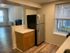 Cozy kitchen space with modern refrigerator, ample cabinetry, and bright window, seamlessly connected to a spacious living area with elegant flooring.