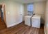 Spacious laundry room with modern washer and dryer, featuring elegant wooden flooring and bright natural lighting.