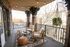 Charming urban balcony with cozy seating, stylish string lights, and lush greenery, perfect for relaxing evenings.
